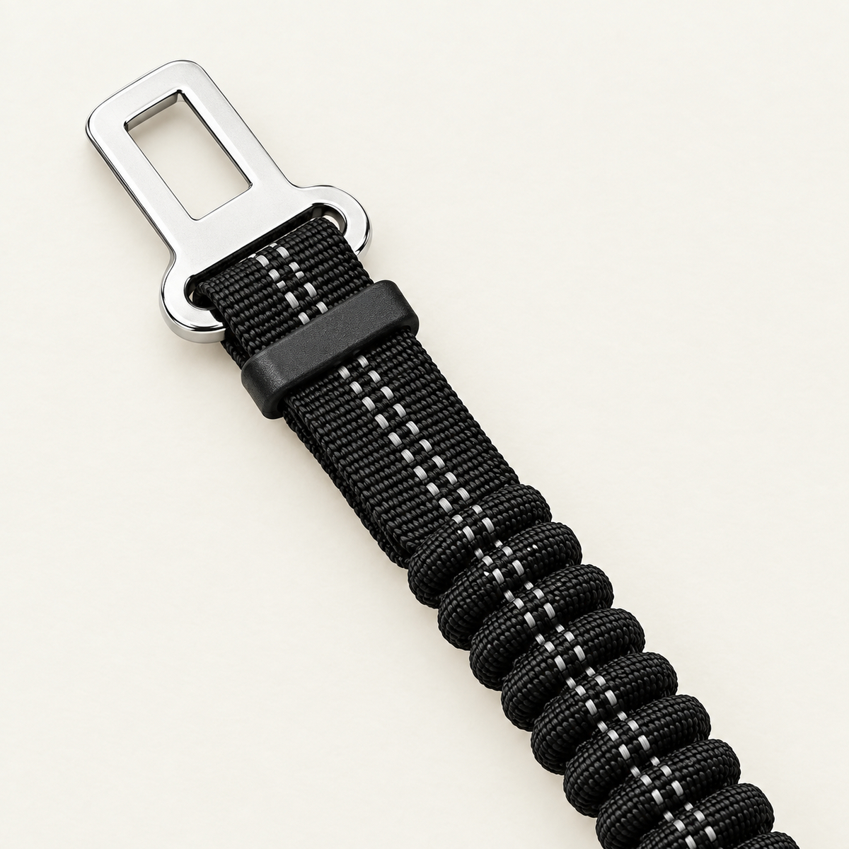 Close detail of the chrome seatbelt buckle tongue and the ribbed elastic bungee section it joins