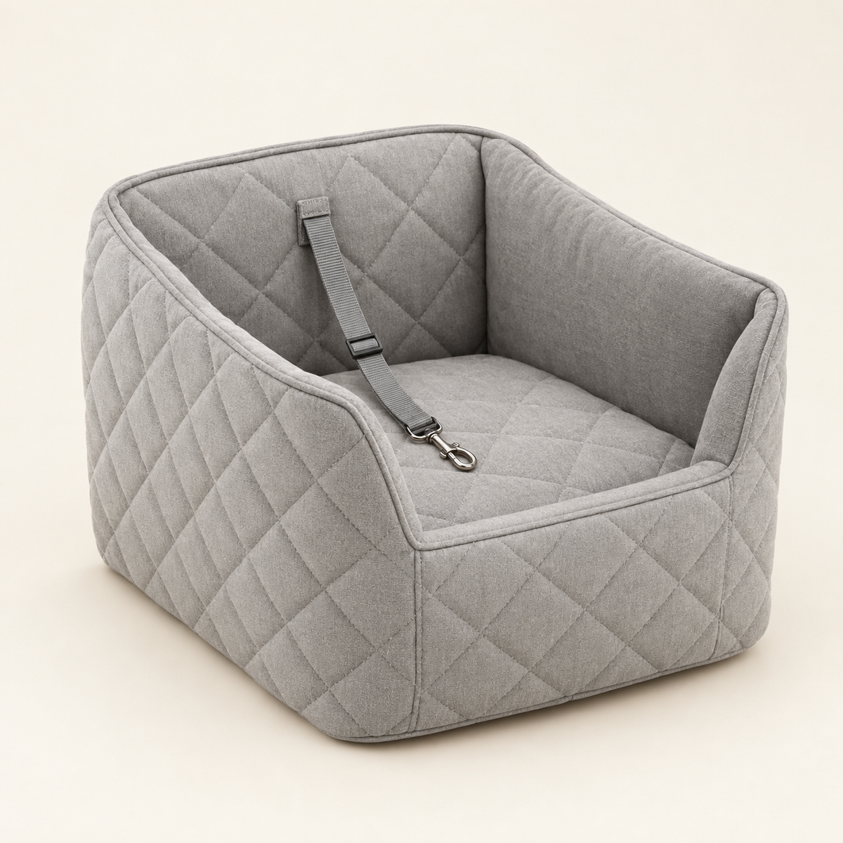 A light grey quilted raised dog car booster seat photographed from a three-quarter angle, empty, showing the tether clip on a warm cream background.