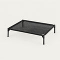 Elevated pet cot with a taut black breathable oxford mesh surface stretched in a slim black steel frame on four splayed legs