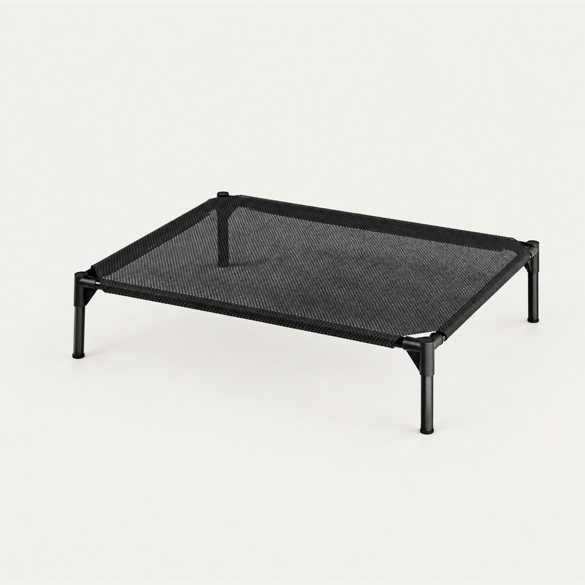 Elevated pet cot with a taut black breathable oxford mesh surface stretched in a slim black steel frame on four splayed legs