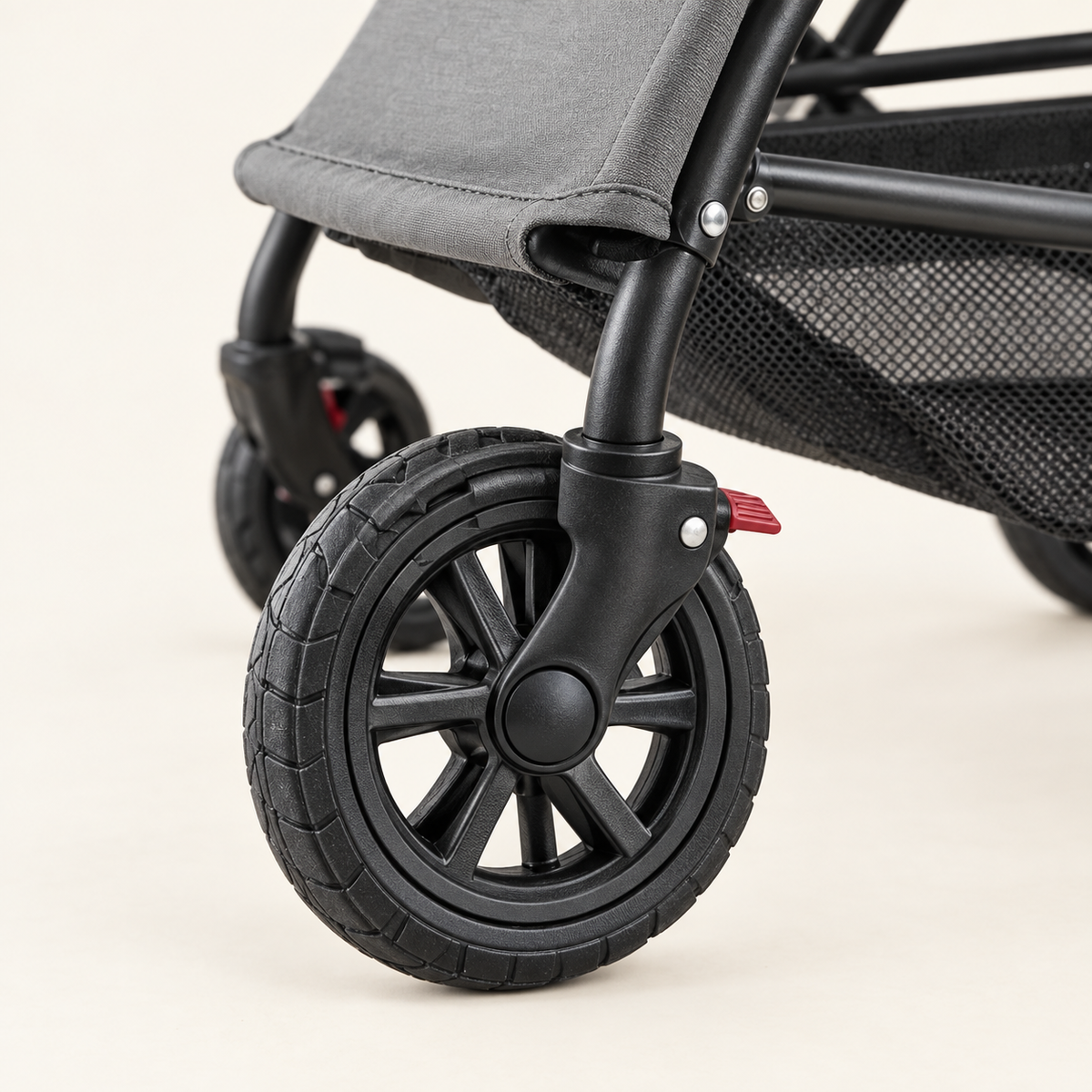 Close detail of the front swivel wheel of the stroller and the small brake lever above it