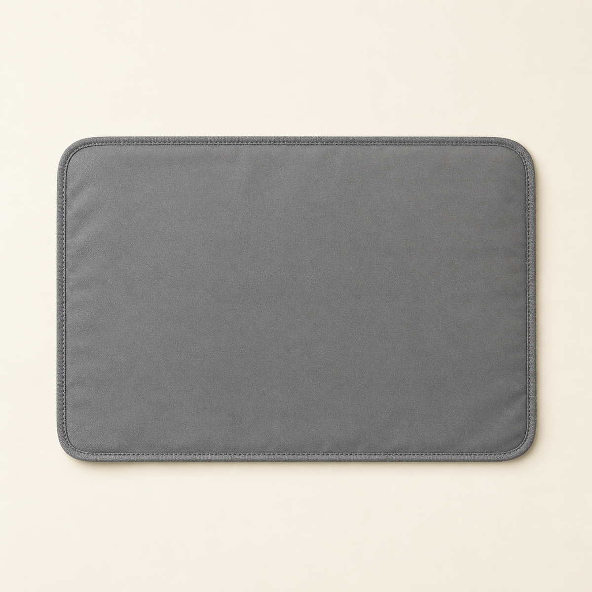 A flat grey waterproof cat litter mat photographed from directly above, lying flat and empty on a warm cream background.