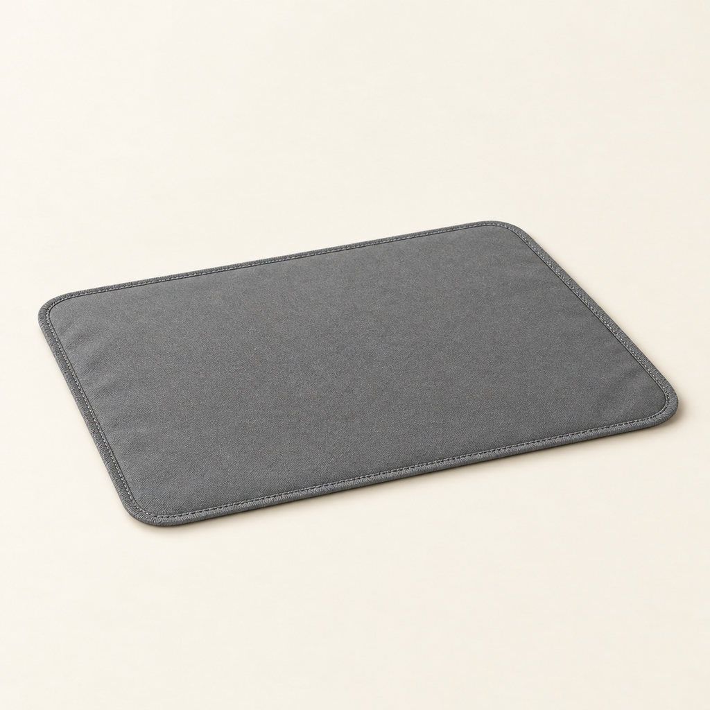 The same litter mat at a low angle showing its raised textured surface and thin waterproof edge on a warm cream background.