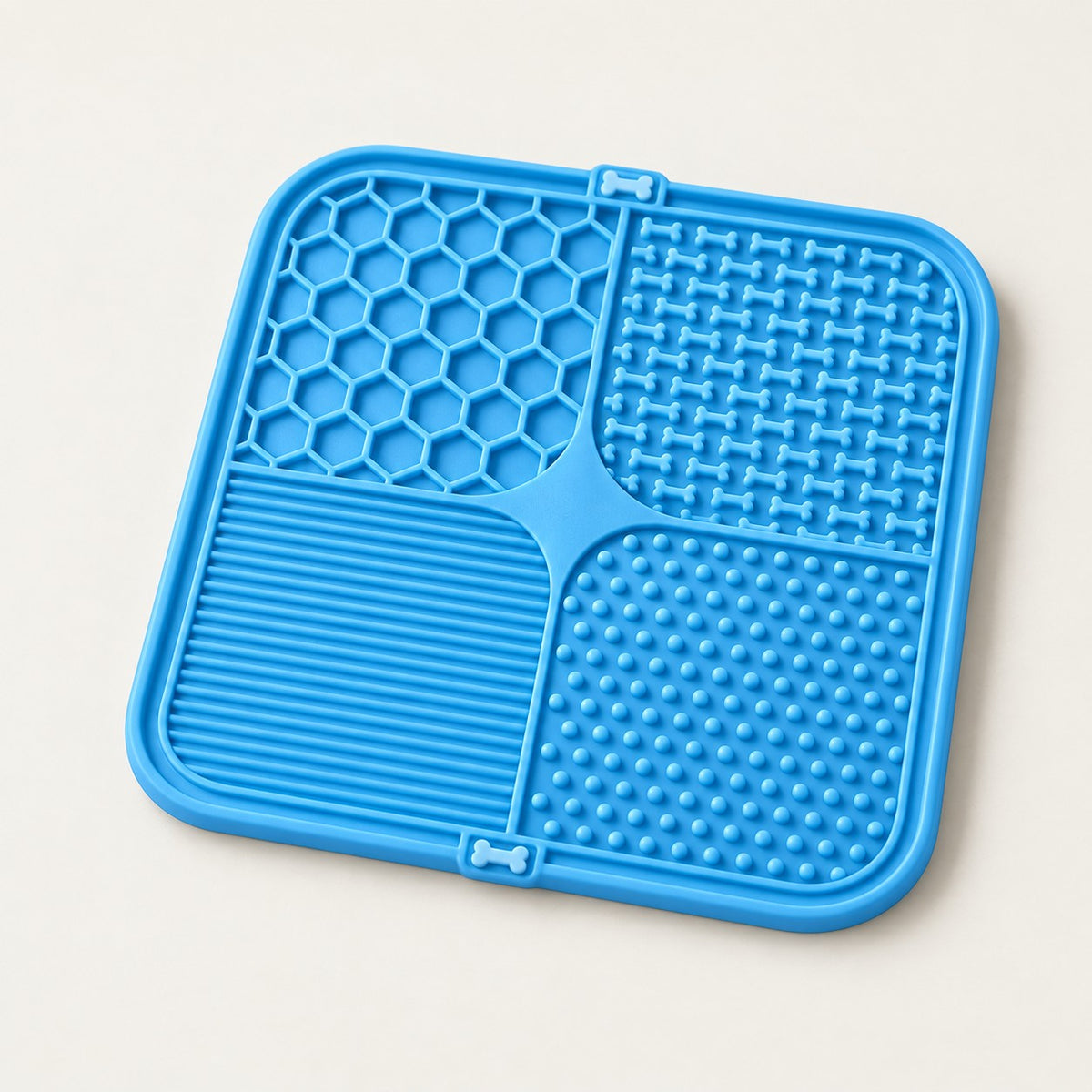 Blue silicone lick mat with four textured zones: honeycomb, raised bones, fine ridges and small nubs