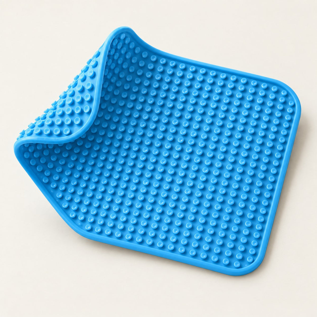 Underside of the blue silicone lick mat showing the full grid of suction cups, one corner peeled up