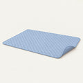 Rectangular dusty blue diamond-quilted self-cooling pet mat laid flat with one corner turned up to show the underside